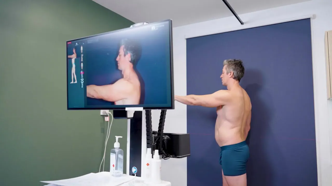 A patient standing in front of the FotoFinder ATBM master at Sunstate while his full-body images appear on screen